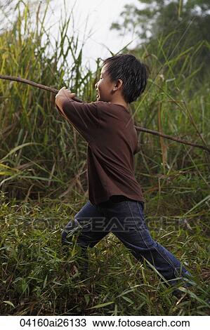 Stock Image - Boy running with stick.. Fotosearch