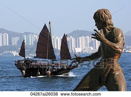 Stock Photo - Chinese junk and Bruce Lee statue at Victoria Harbour, Hong Kong. Fotosearch