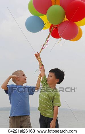 Stock Image - Two boys holding balloons.. Fotosearch