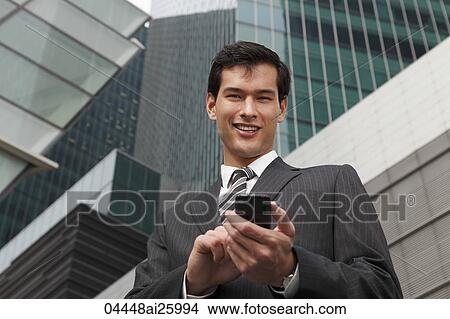 Picture - business man in a suit using mobile phone. Fotosearch
