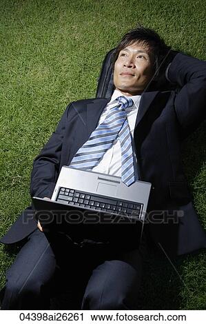 "Businessman resting on grass, open laptop" View Large Photo Image Stock Image - "Businessman resting on grass, open laptop". Fotosearch