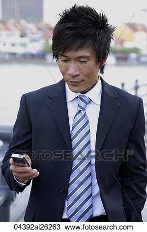 Stock Image - Businessman sending text message. Fotosearch
