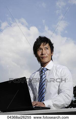 Businessman working on laptop outside View Large Photo Image Stock Photography - Businessman working on laptop outside. Fotosearch