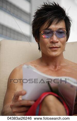 Stock Photograph - Man sitting outside reading magazine. Fotosearch