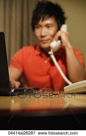 man working at laptop while on phone View Large Photo Image Stock Photo - man working at laptop while on phone. Fotosearch