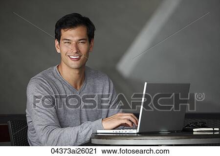 Stock Image - "man working on laptop, smiling at camera". Fotosearch
