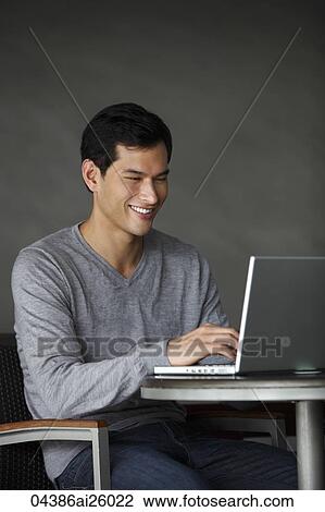 Stock Image - "man working on laptop, smiling". Fotosearch