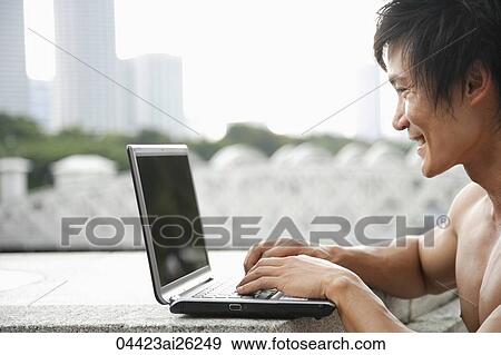 Stock Photo - Profile of man working outside on laptop. Fotosearch