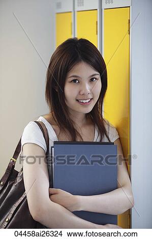 Chinese woman holding folder, smiling. View Large Photo Image Picture - Chinese woman holding folder, smiling.. Fotosearch