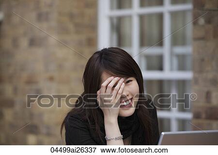 Chinese woman laughing while working on laptop. View Large Photo Image Stock Photo - Chinese woman laughing while working on laptop.. Fotosearch