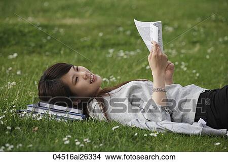 Chinese woman laying on grass reading a book. View Large Photo Image Picture - Chinese woman laying on grass reading a book.. Fotosearch
