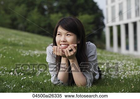 Stock Photography - Chinese woman laying on grass smiling.. Fotosearch