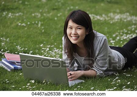 Chinese woman laying on grass working on laptop. View Large Photo Image Stock Photo - Chinese woman laying on grass working on laptop.. Fotosearch