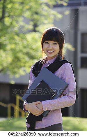 Chinese woman smiling at camera holding folders outside. View Large Photo Image Stock Image - Chinese woman smiling at camera holding folders outside.. Fotosearch