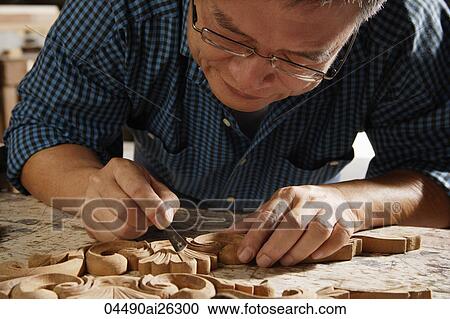 Stock Image - Closeup shot of man carving wood.. Fotosearch