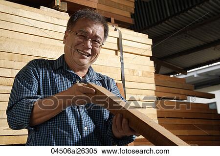 Stock Photography - Mature man inspecting wood.. Fotosearch