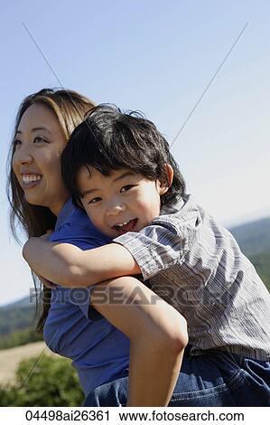 Stock Image - Mother carrying son on back. Fotosearch
