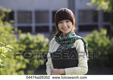 Stock Image - Portrait of Chinese woman smiling holding folders at University. Fotosearch