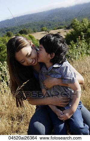 Son kissing mother on cheek. View Large Photo Image Picture - Son kissing mother on cheek.. Fotosearch