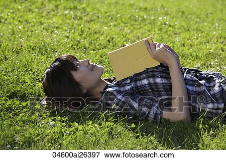 Asian woman laying on grass holding a book. View Large Photo Image Stock Photo - Asian woman laying on grass holding a book.. Fotosearch