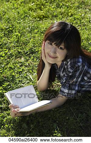 Asian woman laying on grass reading a book. View Large Photo Image Stock Image - Asian woman laying on grass reading a book.. Fotosearch