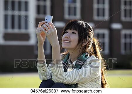 Asian woman looking at phone, outside. View Large Photo Image Stock Photo - Asian woman looking at phone, outside.. Fotosearch