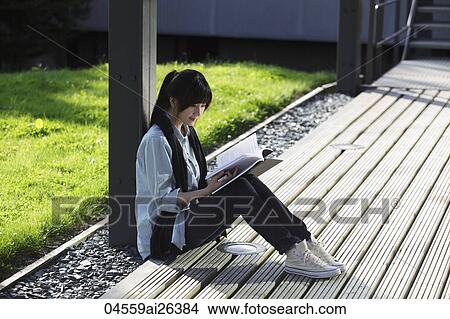 Asian woman sitting on ground reading. View Large Photo Image Picture - Asian woman sitting on ground reading.. Fotosearch