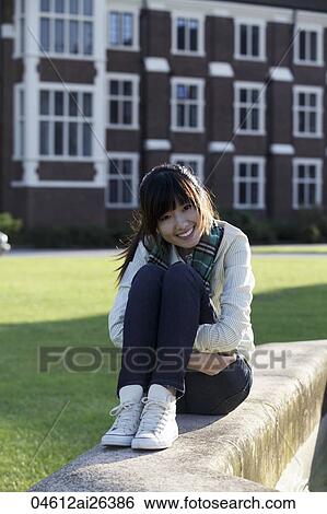 Asian woman sitting on ground, smiling. View Large Photo Image Stock Photograph - Asian woman sitting on ground, smiling.. Fotosearch