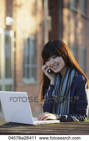 Asian woman working on laptop and talking on phone, outside. View Large Photo Image Stock Image - Asian woman working on laptop and talking on phone, outside.. Fotosearch