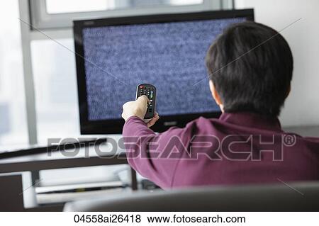 Back shot of man watching TV and holding remote View Large Photo Image Stock Photo - Back shot of man watching TV and holding remote. Fotosearch