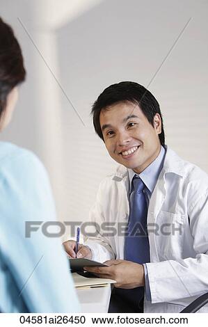 Stock Image - Doctor looking a patient and smiling.. Fotosearch