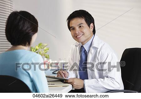 Doctor looking at patient in office View Large Photo Image Stock Photo - Doctor looking at patient in office. Fotosearch