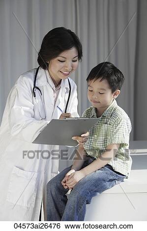 Female doctor giving a young boy a check up View Large Photo Image Stock Photograph - Female doctor giving a young boy a check up. Fotosearch