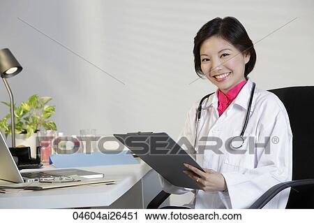 Woman Doctor working at desk and smiling View Large Photo Image Stock Image - Woman Doctor working at desk and smiling. Fotosearch