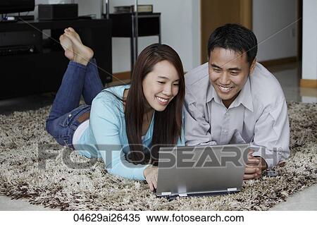 Young couple laying on floor working on laptop computer View Large Photo Image Stock Photography - Young couple laying on floor working on laptop computer. Fotosearch