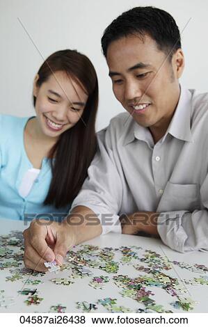 Stock Photo - Young couple putting puzzle together and smiling. Fotosearch