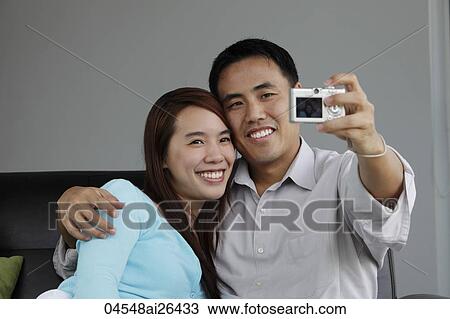 Stock Image - Young couple taking a photograph of each other. Fotosearch