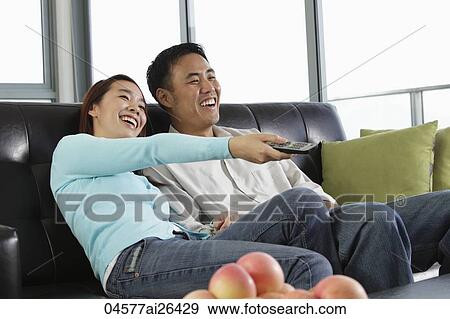 Young couple watching TV and laughing View Large Photo Image Stock Photo - Young couple watching TV and laughing. Fotosearch