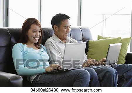 Young couple working on laptops and smiling View Large Photo Image Stock Image - Young couple working on laptops and smiling. Fotosearch