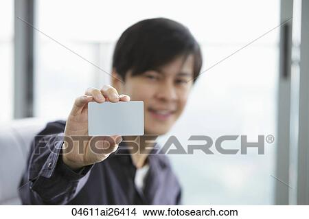 Picture - Young man holding up a credit card. Fotosearch