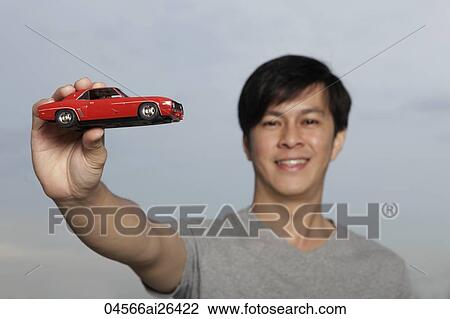Young man holding up red toy car View Large Photo Image Stock Image - Young man holding up red toy car. Fotosearch