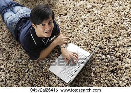Young man laying on stomach working at lap top computer View Large Photo Image Stock Photography - Young man laying on stomach working at lap top computer. Fotosearch