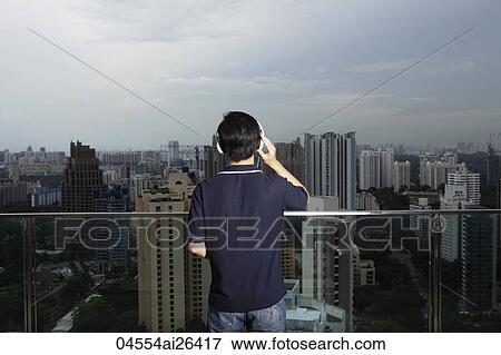 Stock Photo - Young man listening to music and looking at view. Fotosearch