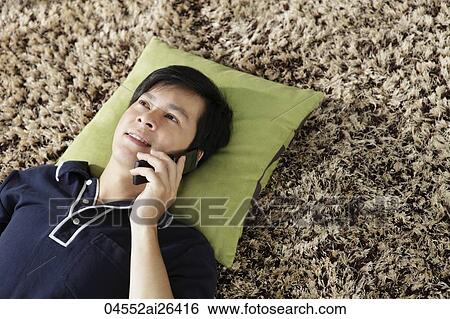 Young man lying on floor talking on phone View Large Photo Image Stock Photograph - Young man lying on floor talking on phone. Fotosearch