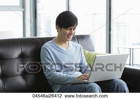 Stock Image - Young man working on his laptop. Fotosearch