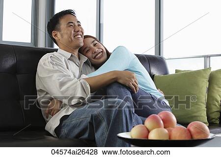 Stock Photo - Young people hugging and smiling at home. Fotosearch