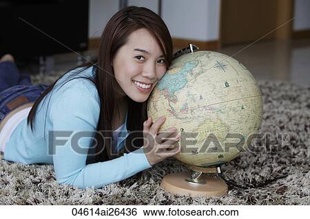 Stock Photograph - Young woman holding globe and smiling. Fotosearch