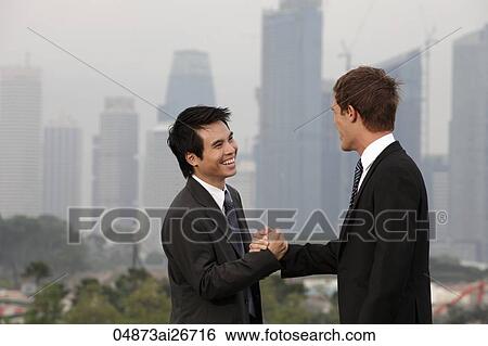 Chinese and Caucasian man shaking hands in front of city sky line View Large Photo Image Stock Photograph - Chinese and Caucasian man shaking hands in front of city sky line. Fotosearch