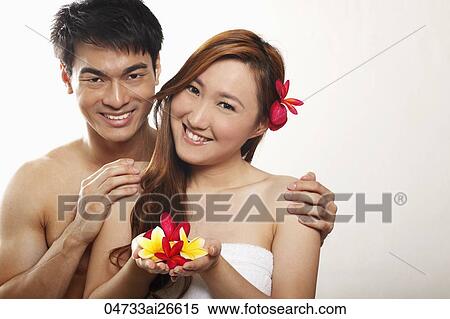 Stock Photography - Chinese couple holding flowers and smiling at camera. Fotosearch