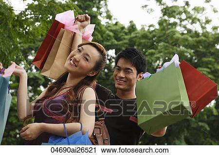 Chinese couple holding shopping bags and smiling View Large Photo Image Stock Image - Chinese couple holding shopping bags and smiling. Fotosearch